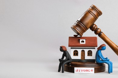 Photo of Word Divorce near house model, plasticine people figures and wooden gavel on light grey background, space for text