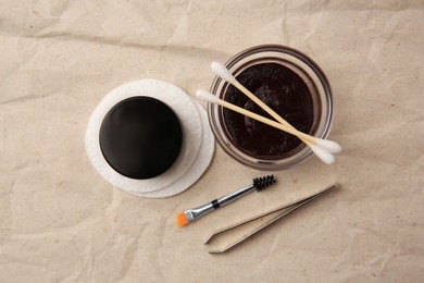Photo of Flat lay composition with eyebrow henna and tools on crumpled paper