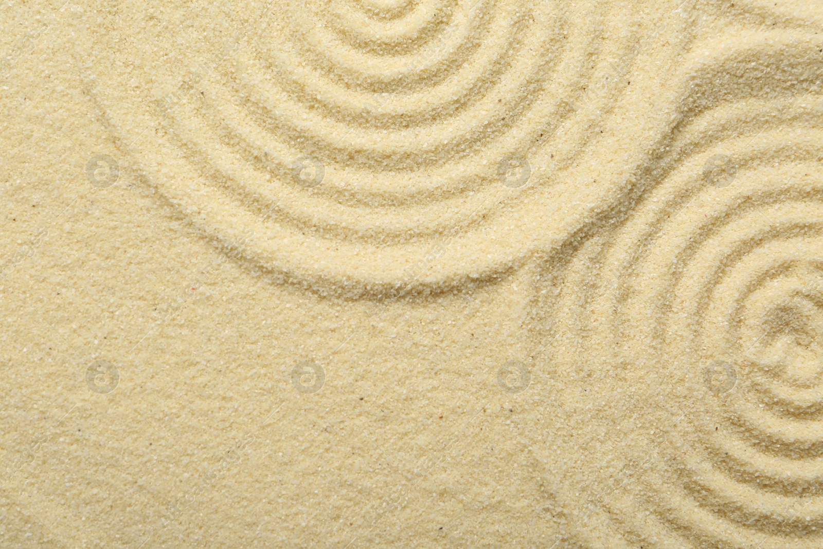 Photo of Zen rock garden. Circle patterns on beige sand, top view