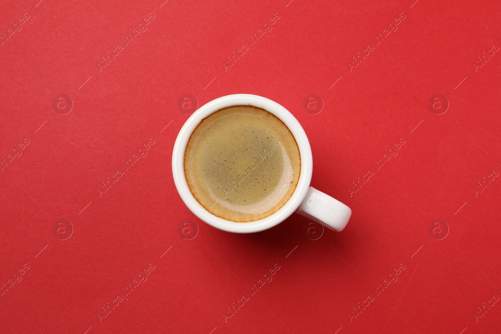 Photo of Aromatic coffee in cup on red background, top view