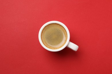 Photo of Aromatic coffee in cup on red background, top view