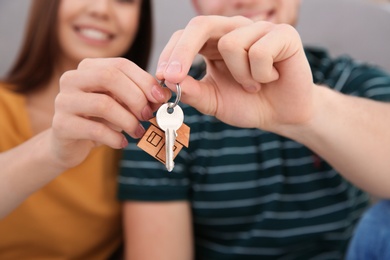 Photo of Young couple with key from their new house indoors, closeup. Moving day