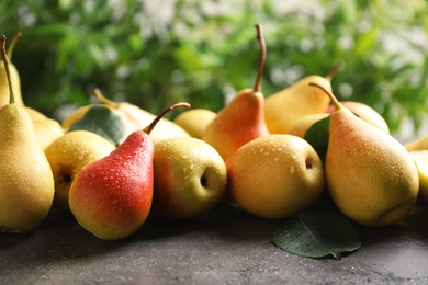 Photo of Ripe pears on grey table against blurred background