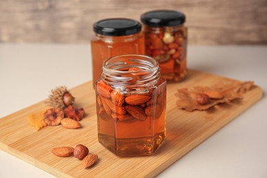 Photo of Jars with different nuts and honey on white table