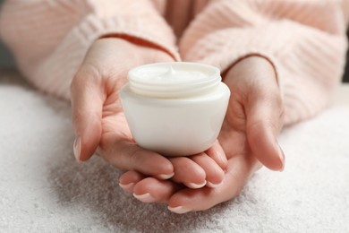 Photo of Woman with jar of hand cream over snow, closeup