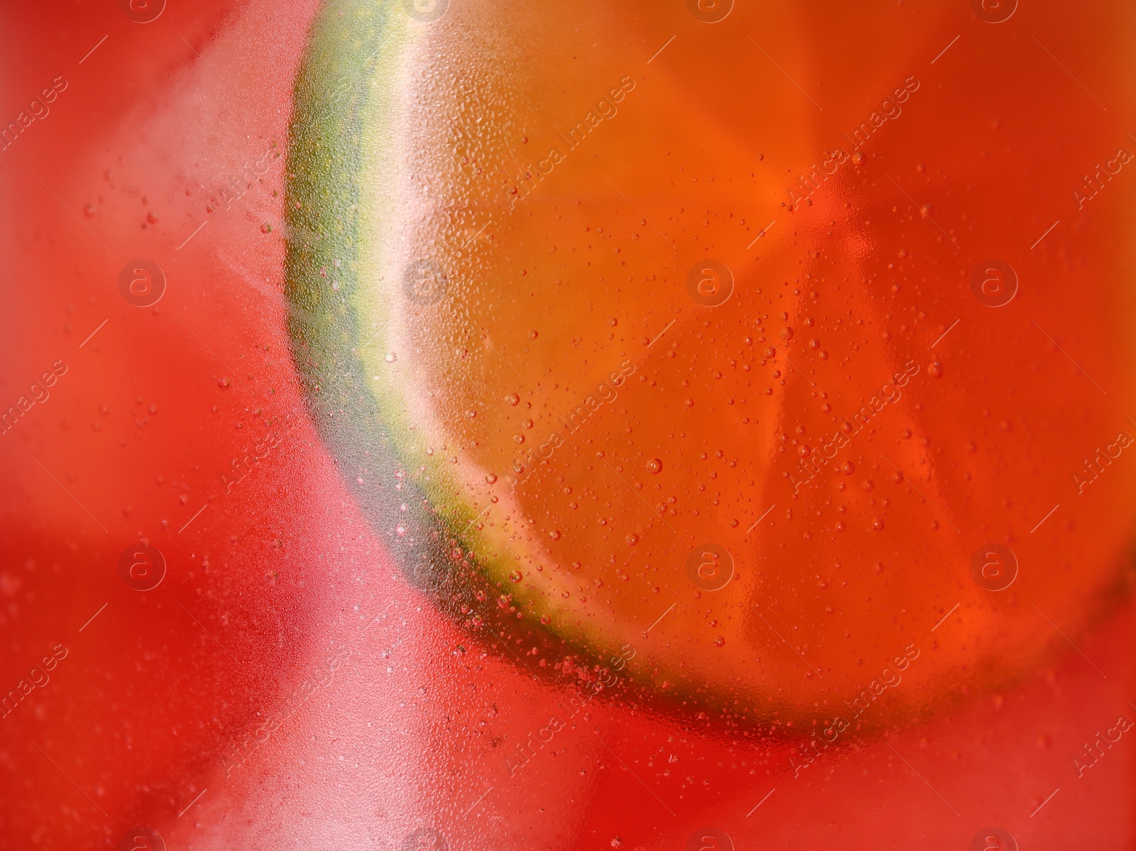 Photo of Glass of refreshing drink with ice cubes and lime slice as background, closeup