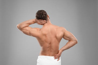 Photo of Man suffering from back and neck pain on grey background, back view