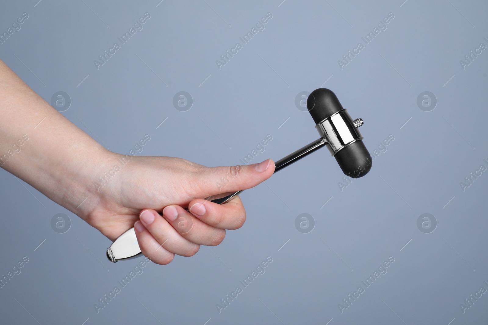 Photo of Woman with reflex hammer on grey background, closeup. Nervous system diagnostic