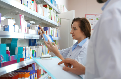 Image of Professional pharmacists near shelves in modern drugstore