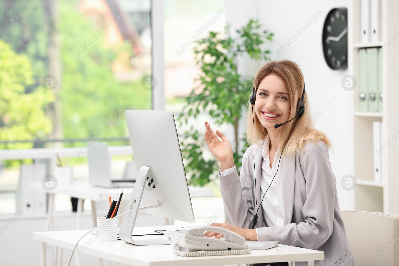 Photo of Female receptionist with headset at desk in office