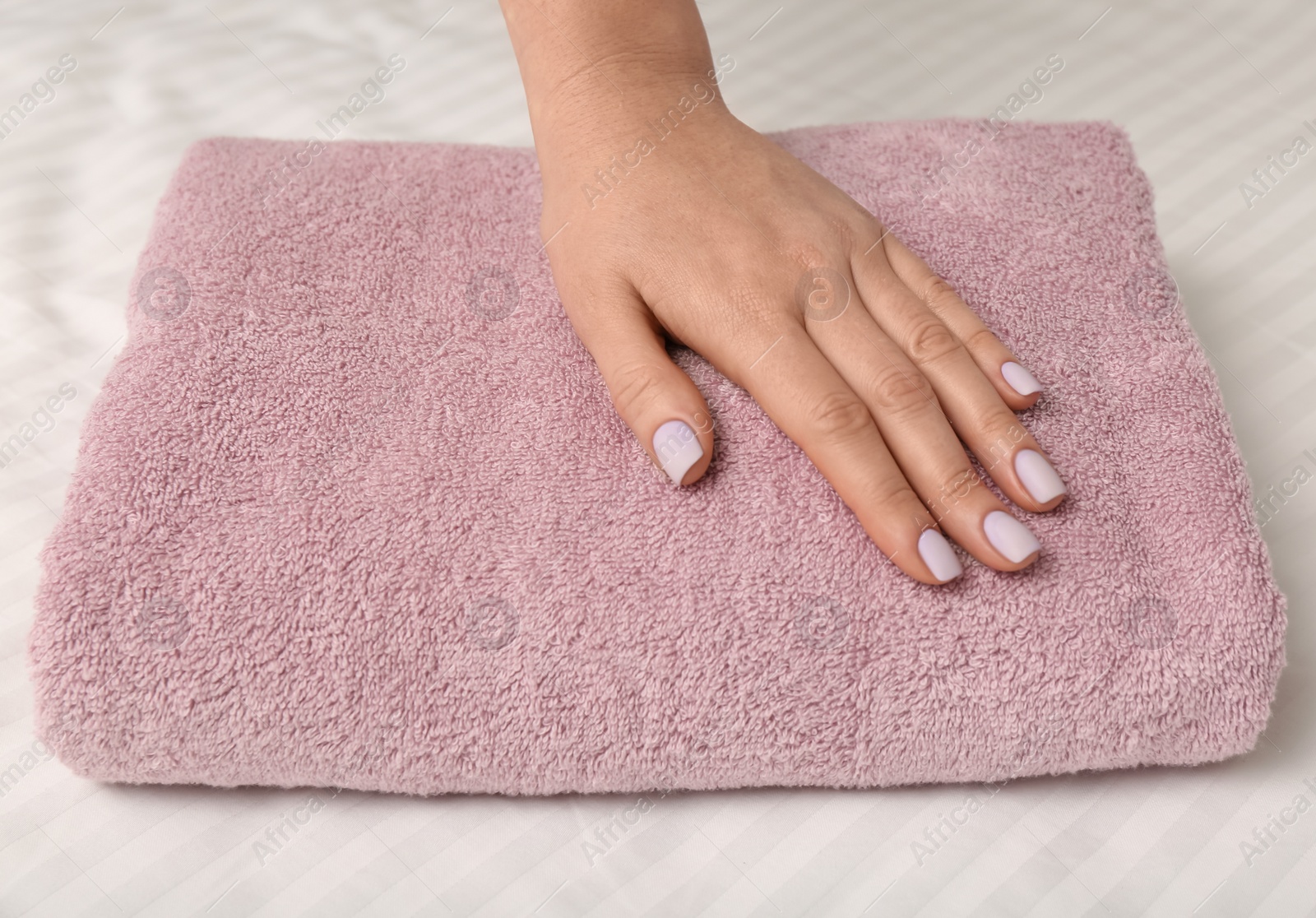 Photo of Woman touching soft towel on bed, closeup