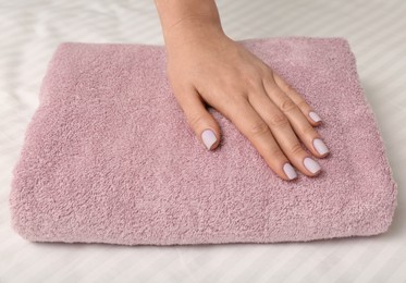 Photo of Woman touching soft towel on bed, closeup