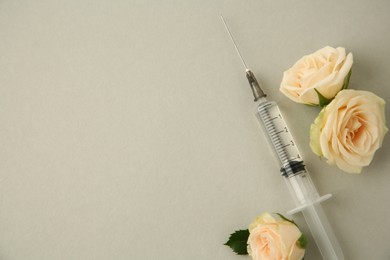 Photo of Medical syringe and rose flowers on light grey background, flat lay. Space for text