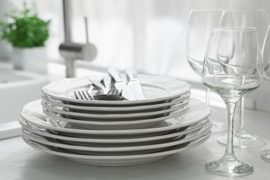 Photo of Different clean dishware, cutlery and glasses on countertop in kitchen, closeup