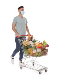 Man with protective mask and shopping cart full of groceries on white background