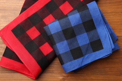 Photo of Folded red and blue checkered bandanas on wooden table, flat lay