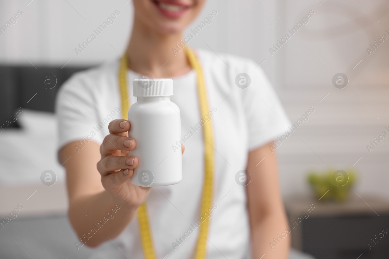 Photo of Woman holding bottle of pills in room, closeup. Weight loss