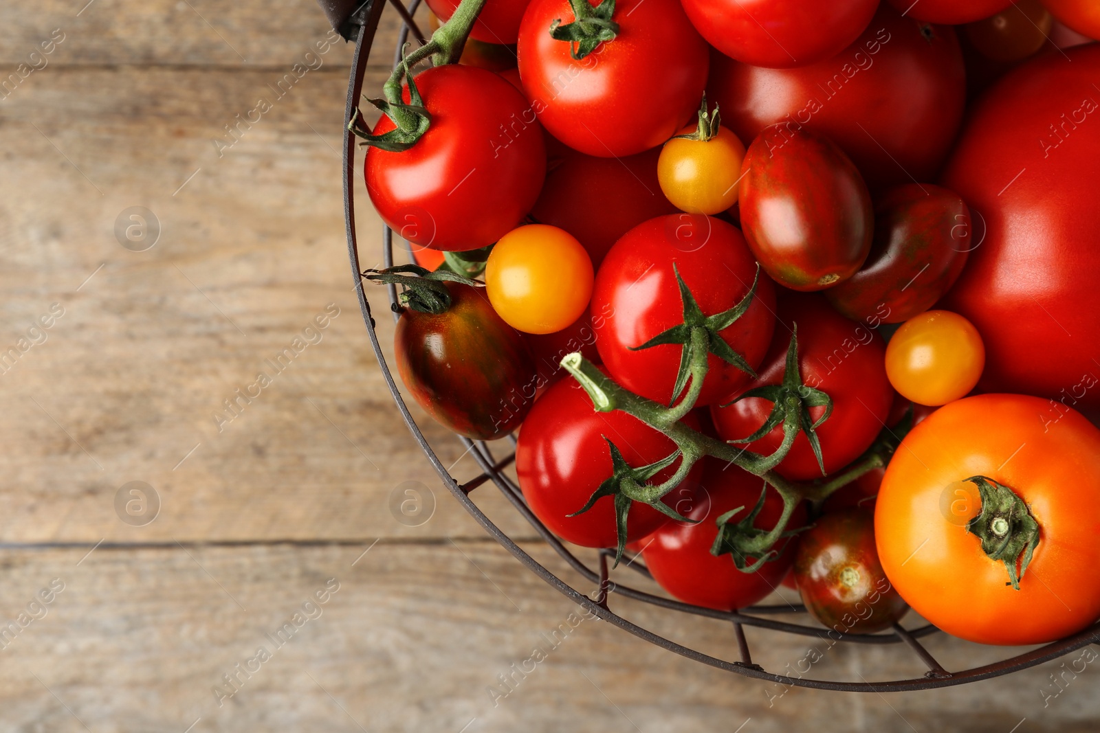 Photo of Fresh ripe tomatoes in basket on wooden table, top view