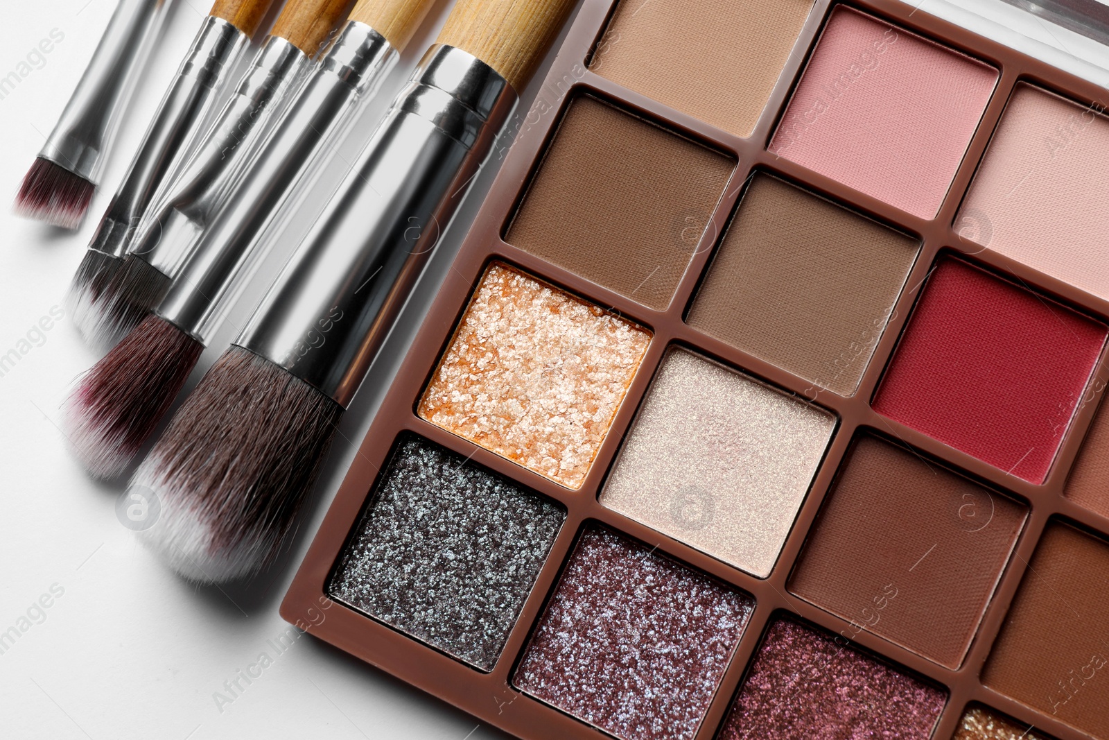 Photo of Beautiful eye shadow palette and brushes on white table, flat lay