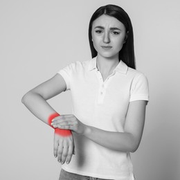 Image of Woman suffering from rheumatism on light background. Black and white effect with red accent in painful area