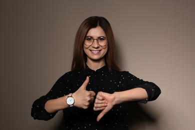 Woman showing THUMB UP and DOWN gesture in sign language on color background