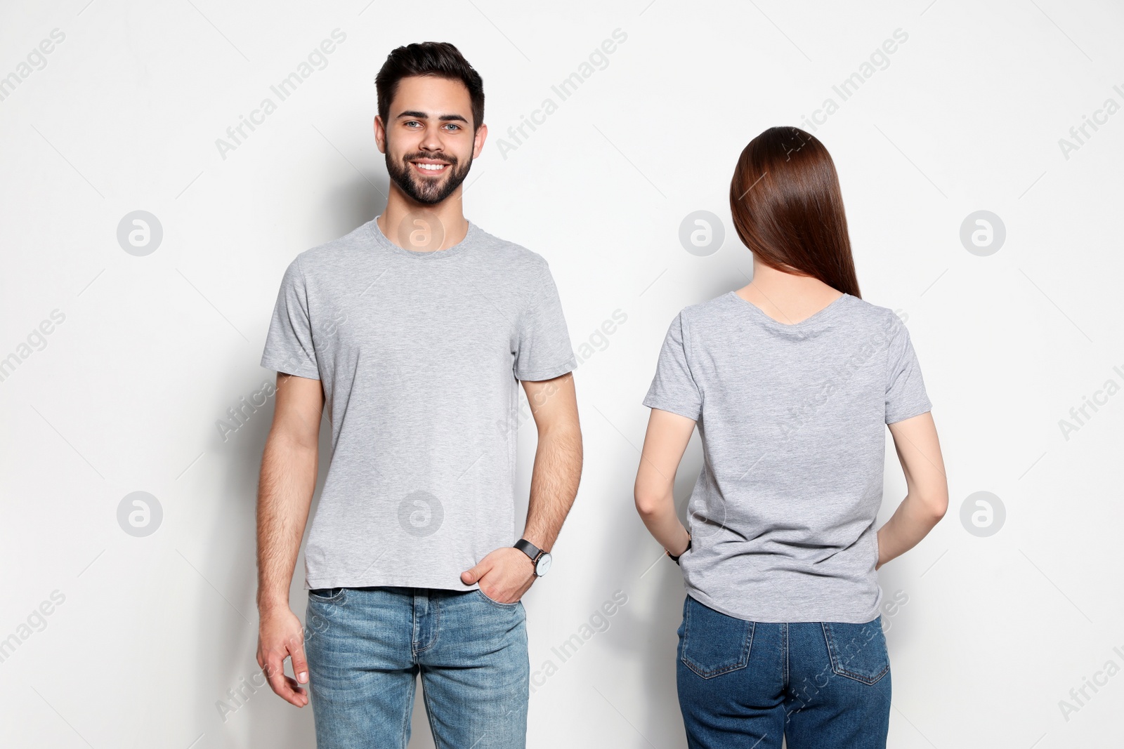 Photo of Young people in t-shirts on light background. Mock up for design