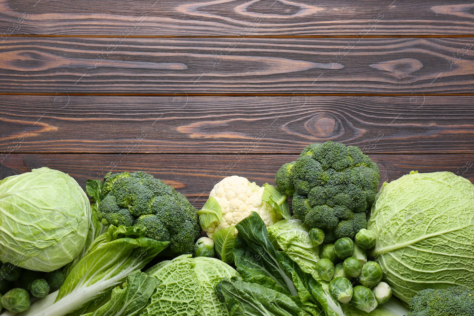 Photo of Many different types of fresh cabbage on wooden table, flat lay. Space for text