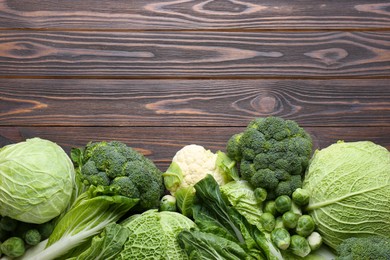 Many different types of fresh cabbage on wooden table, flat lay. Space for text