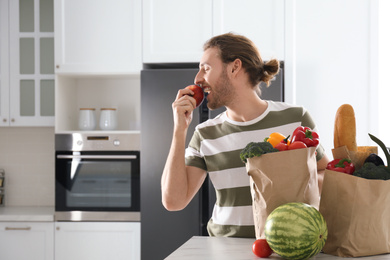 Man with fresh products near modern refrigerator in kitchen