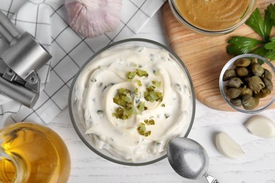 Photo of Tasty tartar sauce and ingredients on white wooden table, flat lay