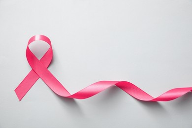 Pink ribbon on light grey background, top view. Breast cancer awareness concept