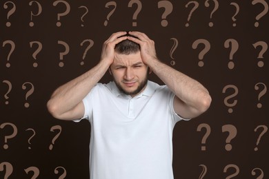 Image of Amnesia. Confused man and question marks on brown background