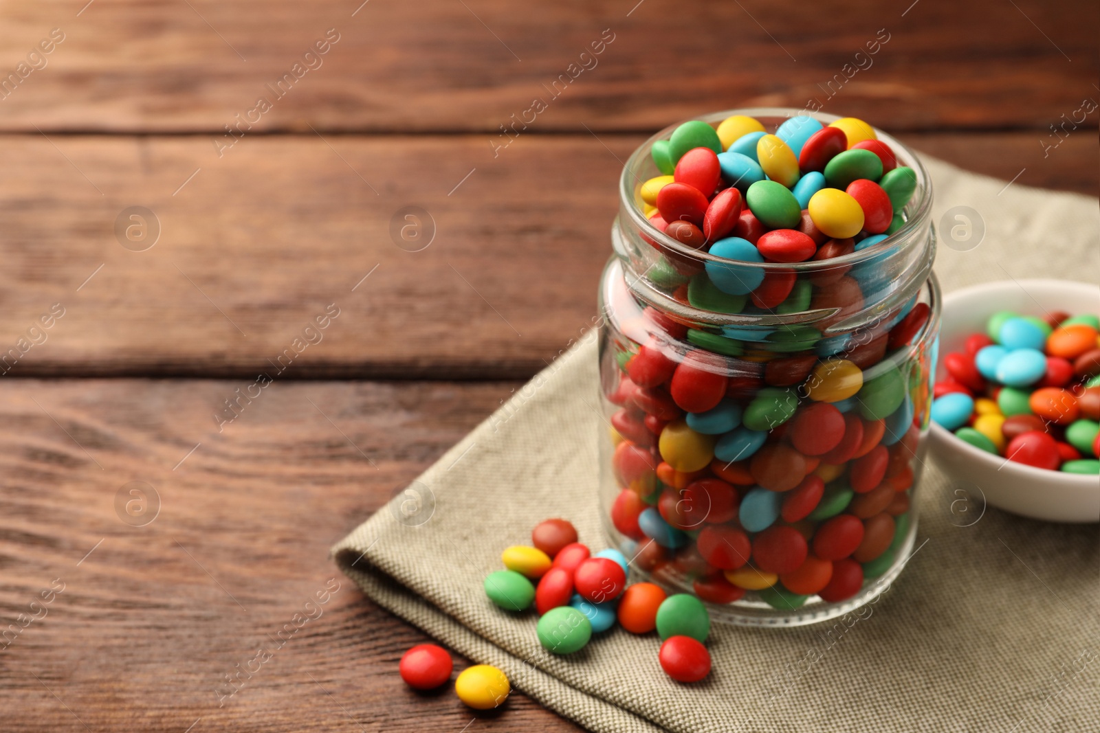 Photo of Tasty colorful candies on wooden table, space for text