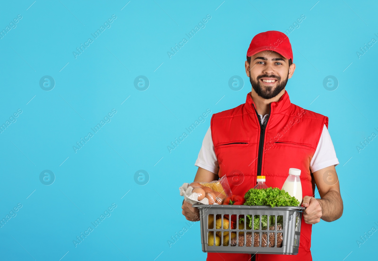 Photo of Man holding basket with fresh products on color background, space for text. Food delivery service