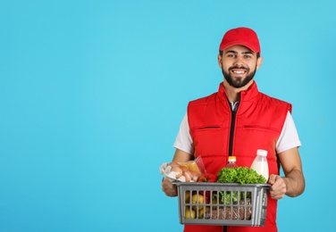 Man holding basket with fresh products on color background, space for text. Food delivery service