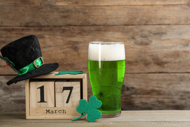 Photo of Composition with green beer and clover on wooden table. St. Patrick's Day celebration