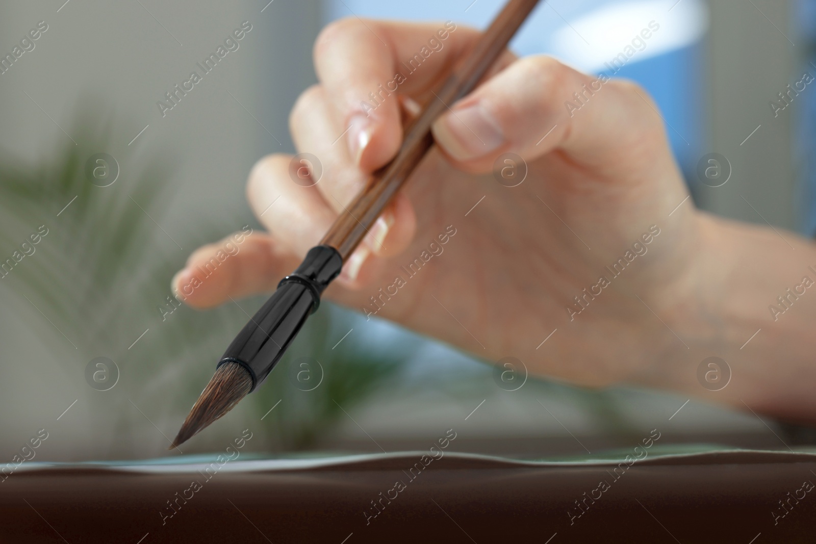 Photo of Woman painting with watercolor at table indoors, closeup