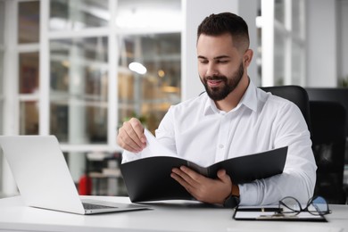 Photo of Smiling man working at table in office. Lawyer, businessman, accountant or manager