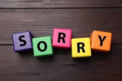 Image of Apology. Word Sorry made of colorful cubes on wooden table, top view