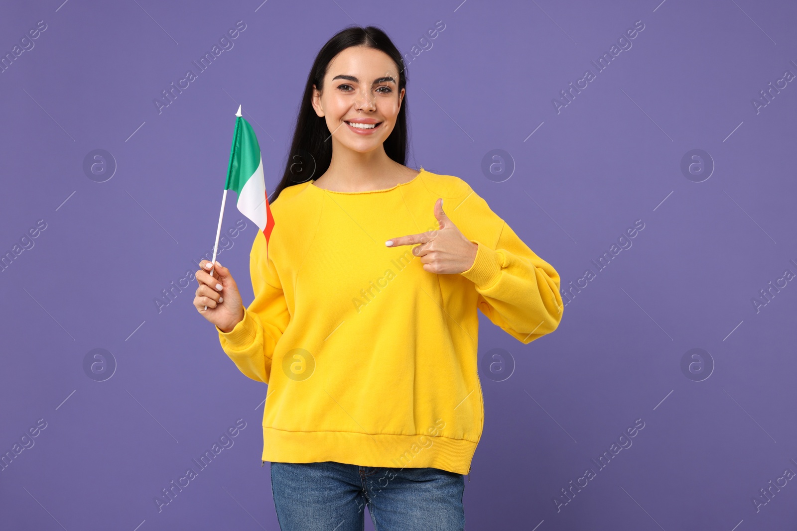 Photo of Happy young woman pointing at flag of Italy on violet background