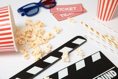 Photo of Clapper, popcorn and tickets on white background. Cinema snack