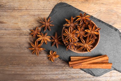 Photo of Aromatic cinnamon sticks and anise stars on wooden table, flat lay