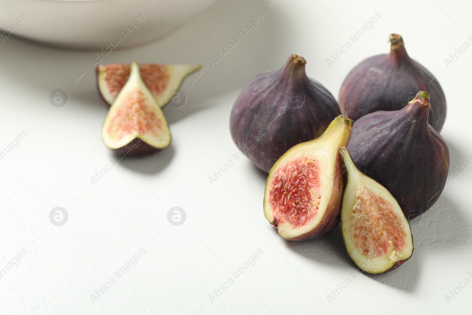 Photo of Whole and cut tasty fresh figs on white table