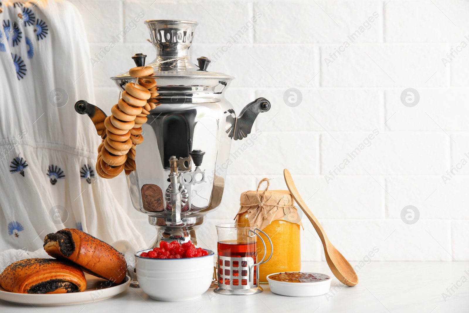 Photo of Traditional Russian samovar and treats on white table. Space for text