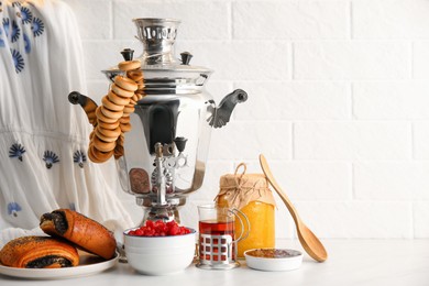 Photo of Traditional Russian samovar and treats on white table. Space for text