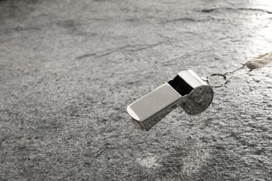 Photo of Referee equipment. Metal whistle on grey textured background, closeup and space for text