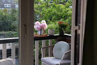 Photo of Different plants on railings and chair at cozy balcony outdoors