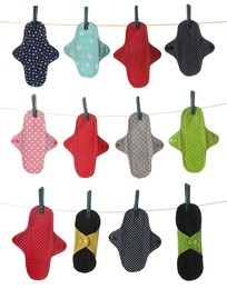 Many different cloth menstrual pads hanging on laundry line, white background