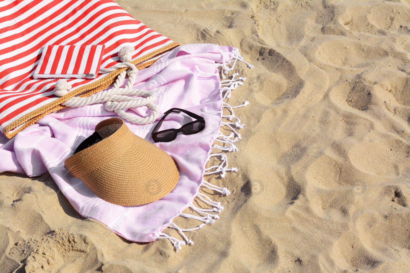 Photo of Stylish striped bag with beach accessories on sand. Space for text