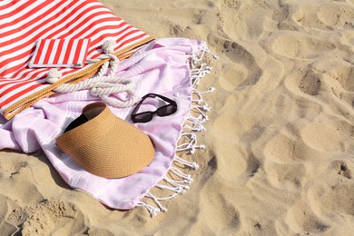 Stylish striped bag with beach accessories on sand. Space for text